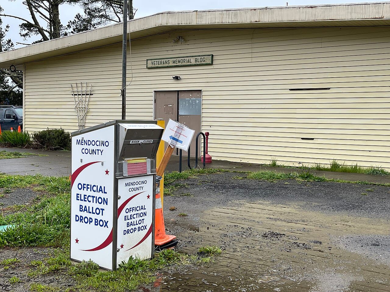 An official county election ballot drop box standing outside a community building in California