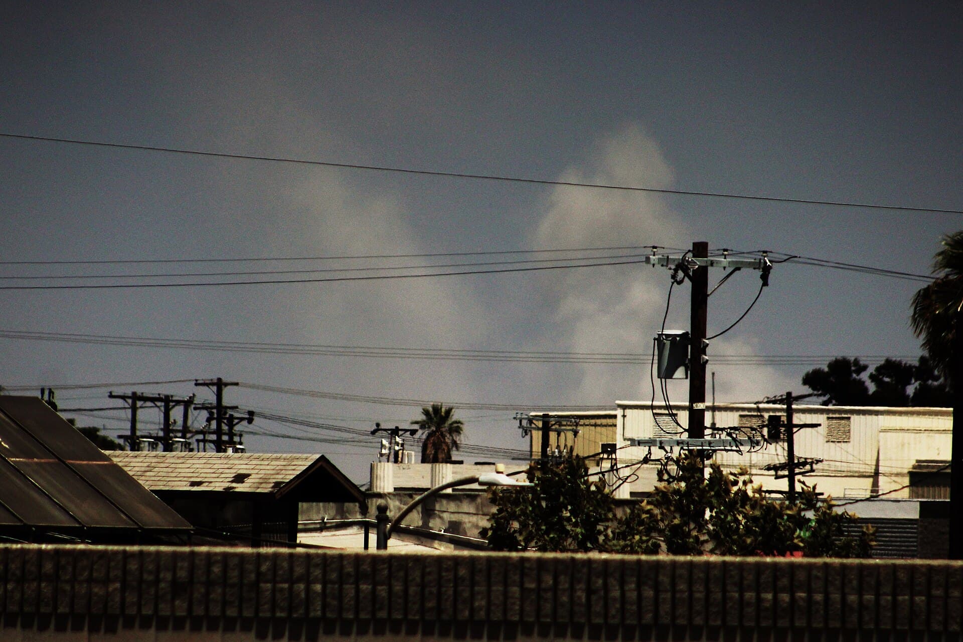 Smoke rises from the cold-storage warehouse fire in Boyle Heights, Los Angeles, on June 19, 2026, two days after it began, seen from Interstate 110. Contrast adjusted by the photographer.