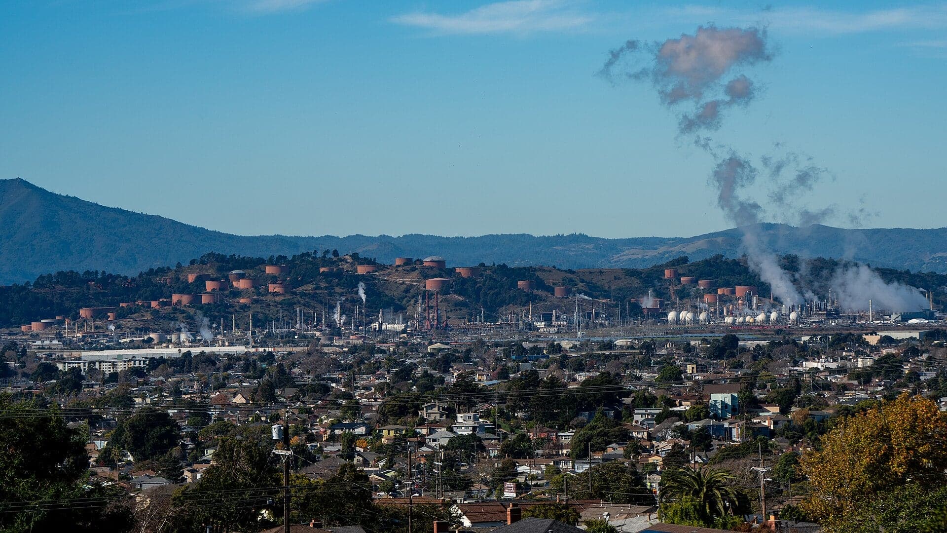 Homes in Richmond, California, in the foreground with the Chevron refinery's tanks and steam plumes beyond and Mount Tamalpais on the horizon