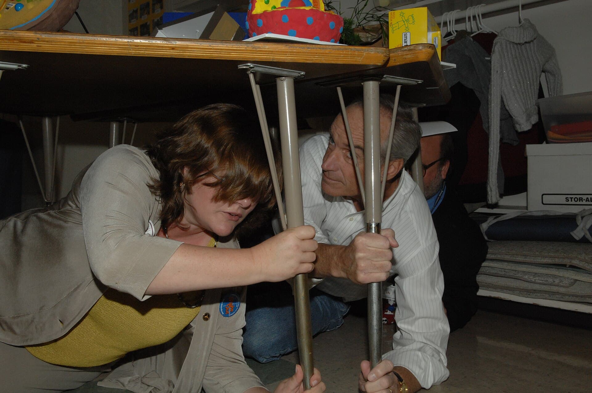 Then-Interior Secretary Dirk Kempthorne, right, drops, covers and holds on under a classroom table during the first Great Southern California ShakeOut drill at a Los Angeles County school, Nov. 13, 2008 (file photo)