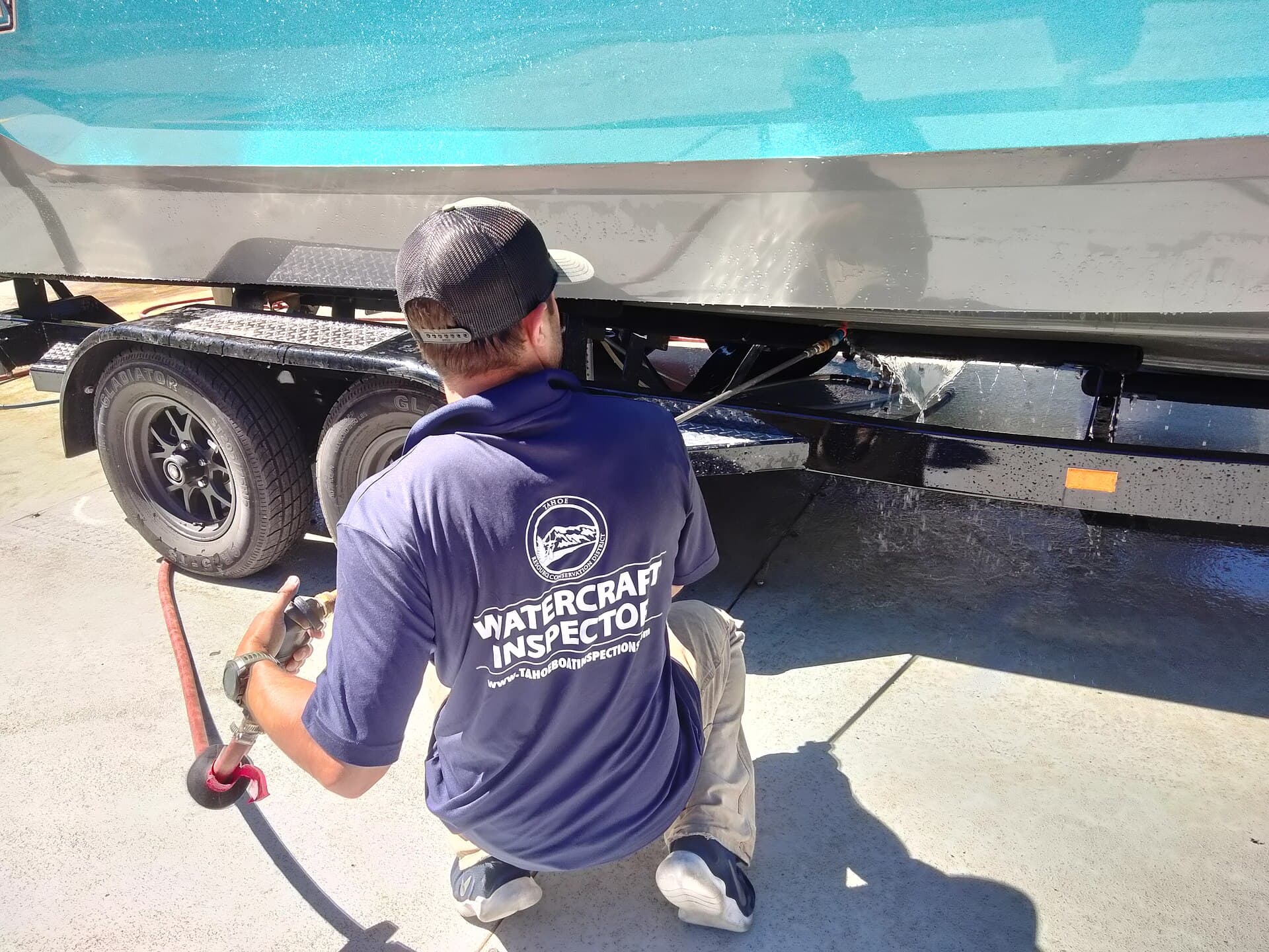 A Lake Tahoe Watercraft Inspection Program inspector hoses down a boat and trailer to prevent the spread of invasive mussels, June 28, 2022 (file photo)