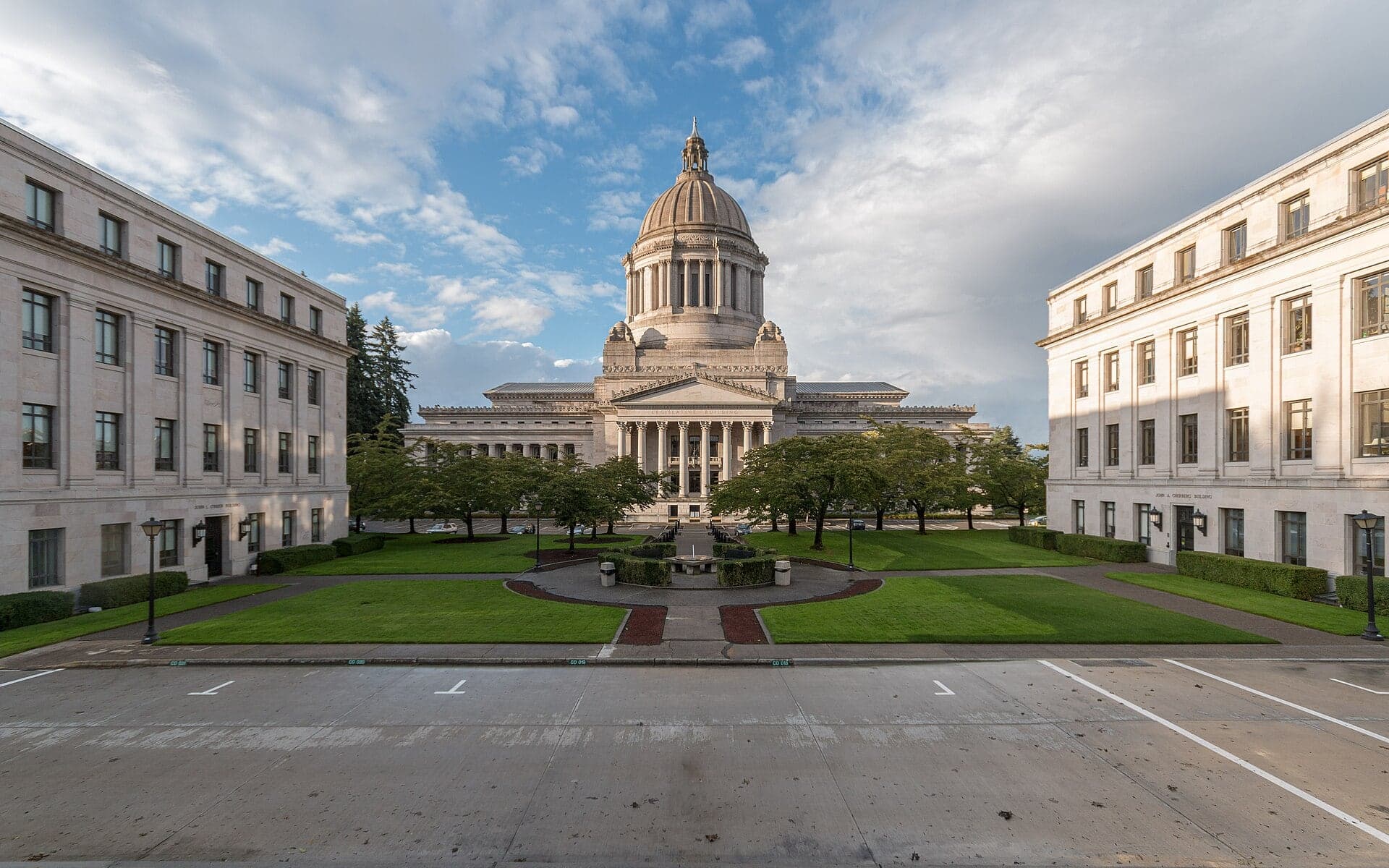 The domed Legislative Building of the Washington State Capitol in Olympia, framed by two neighboring office buildings across an empty plaza