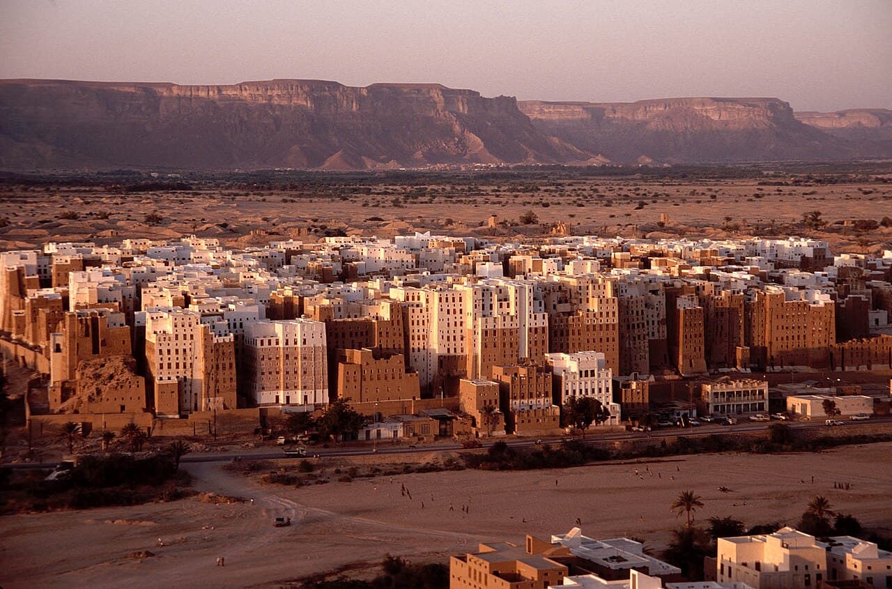 The mudbrick tower houses of Shibam in Wadi Hadhramaut, Yemen, beneath a desert escarpment